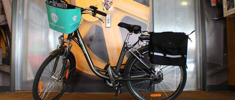 Una bicicleta con una cesta y una bolsa sujetas en la parte trasera, estacionada frente a un ascensor.