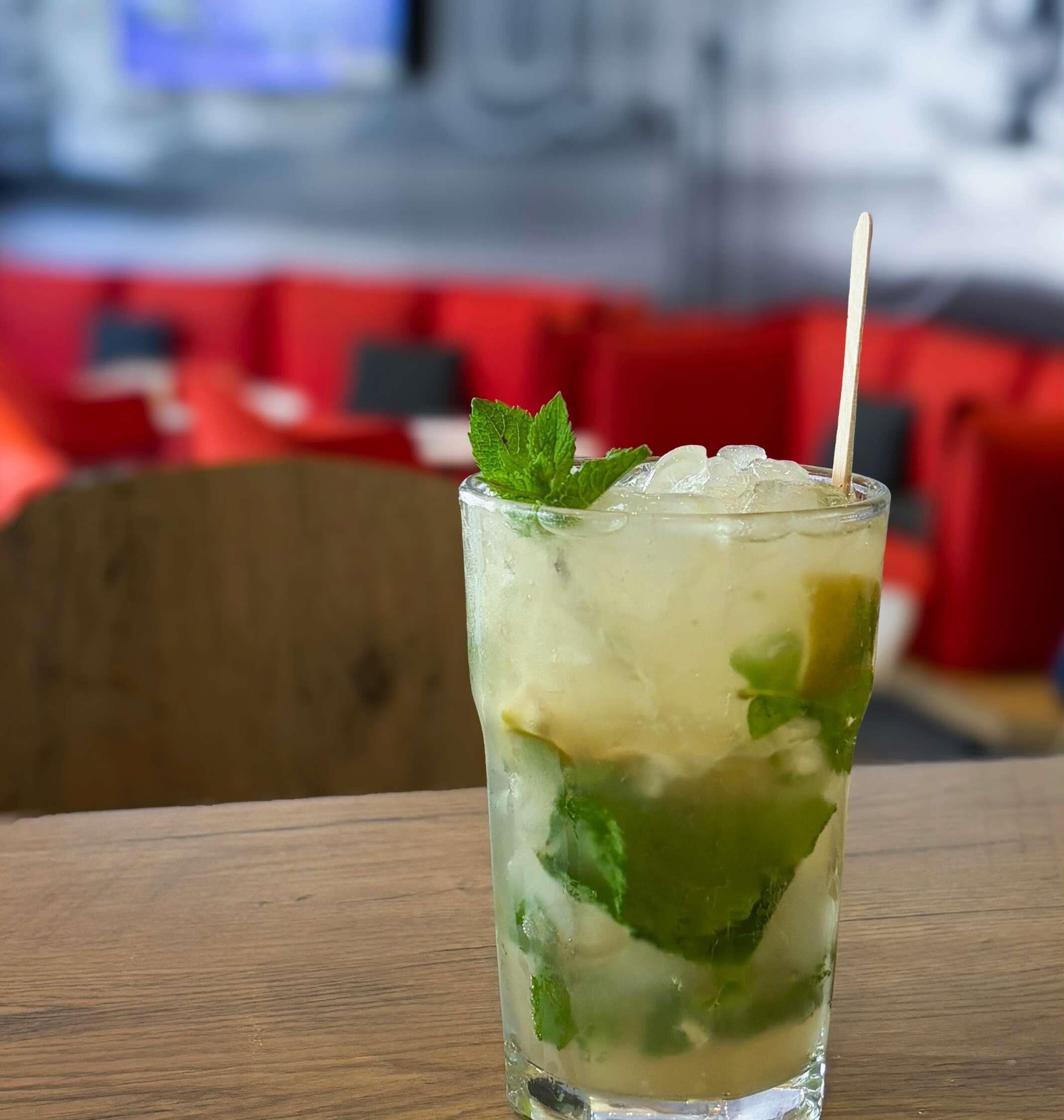 A glass of iced drink with mint leaves on a wooden table.