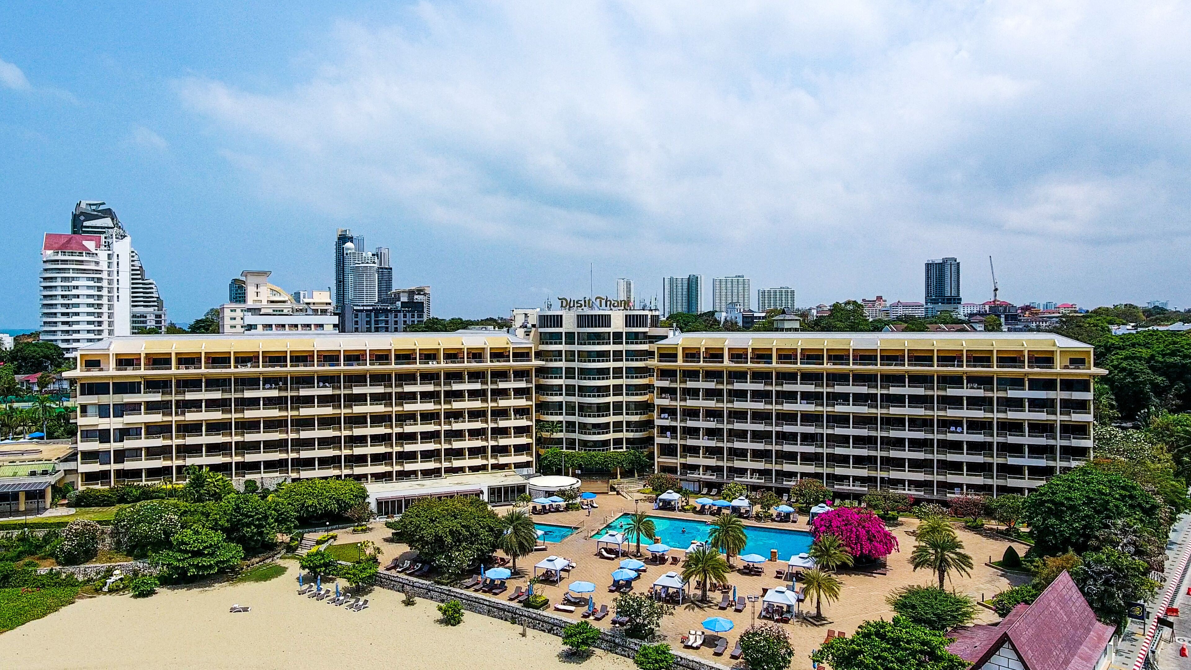 Een hotel met meerdere verdiepingen, een zwembad en een strandgedeelte.