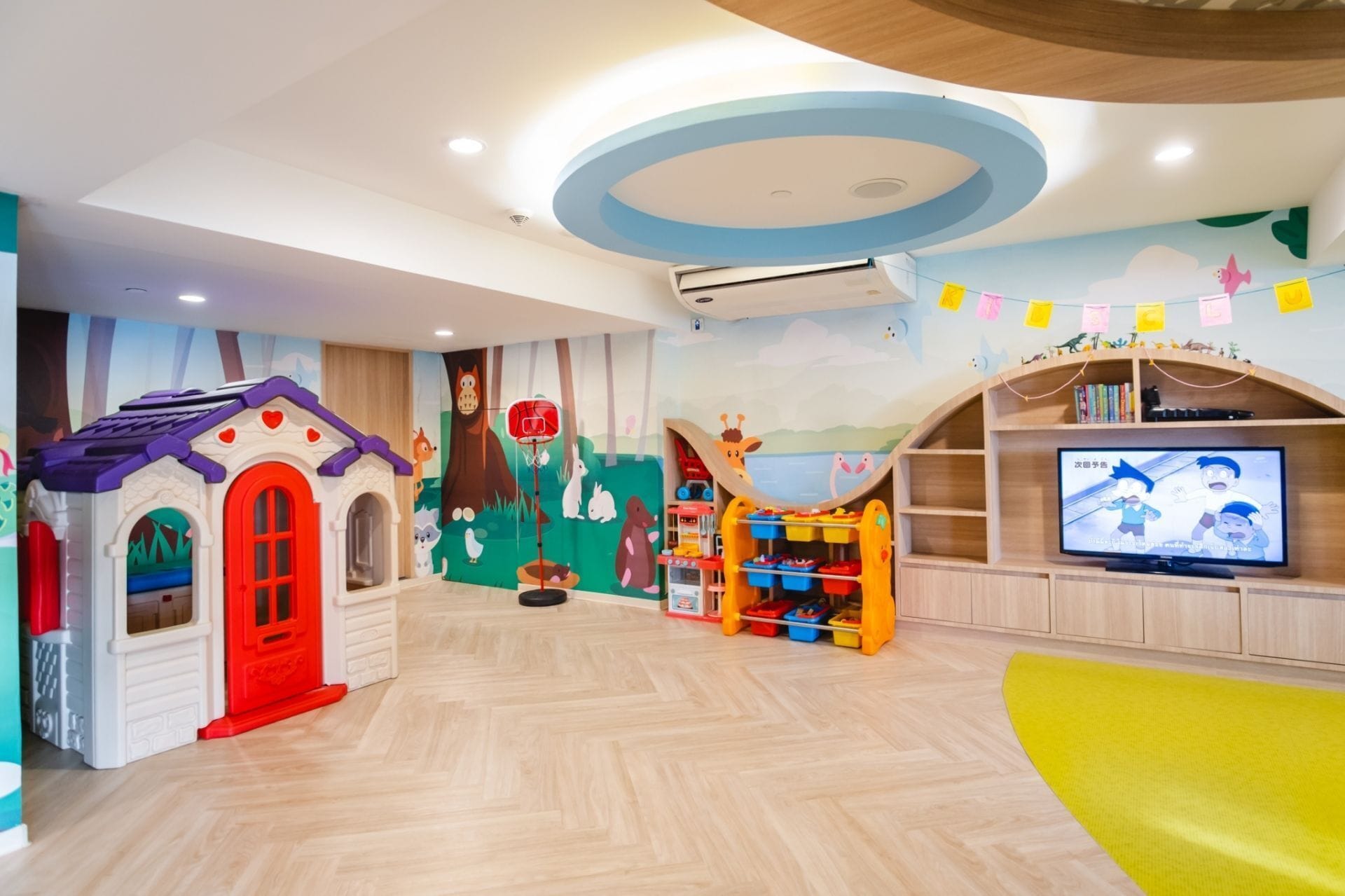 A children's playroom with a playhouse, a basketball hoop, and a television.
