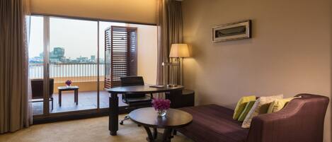 Una habitación de hotel con balcón, sofá, mesa y lámpara.