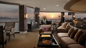 A modern living room with a view of the sunset over the water, a dining area, and a kitchen. - Dusit Thani Pattaya (Pattaya)