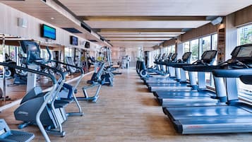 Un gimnasio con cintas de correr, elípticas y equipos de pesas.