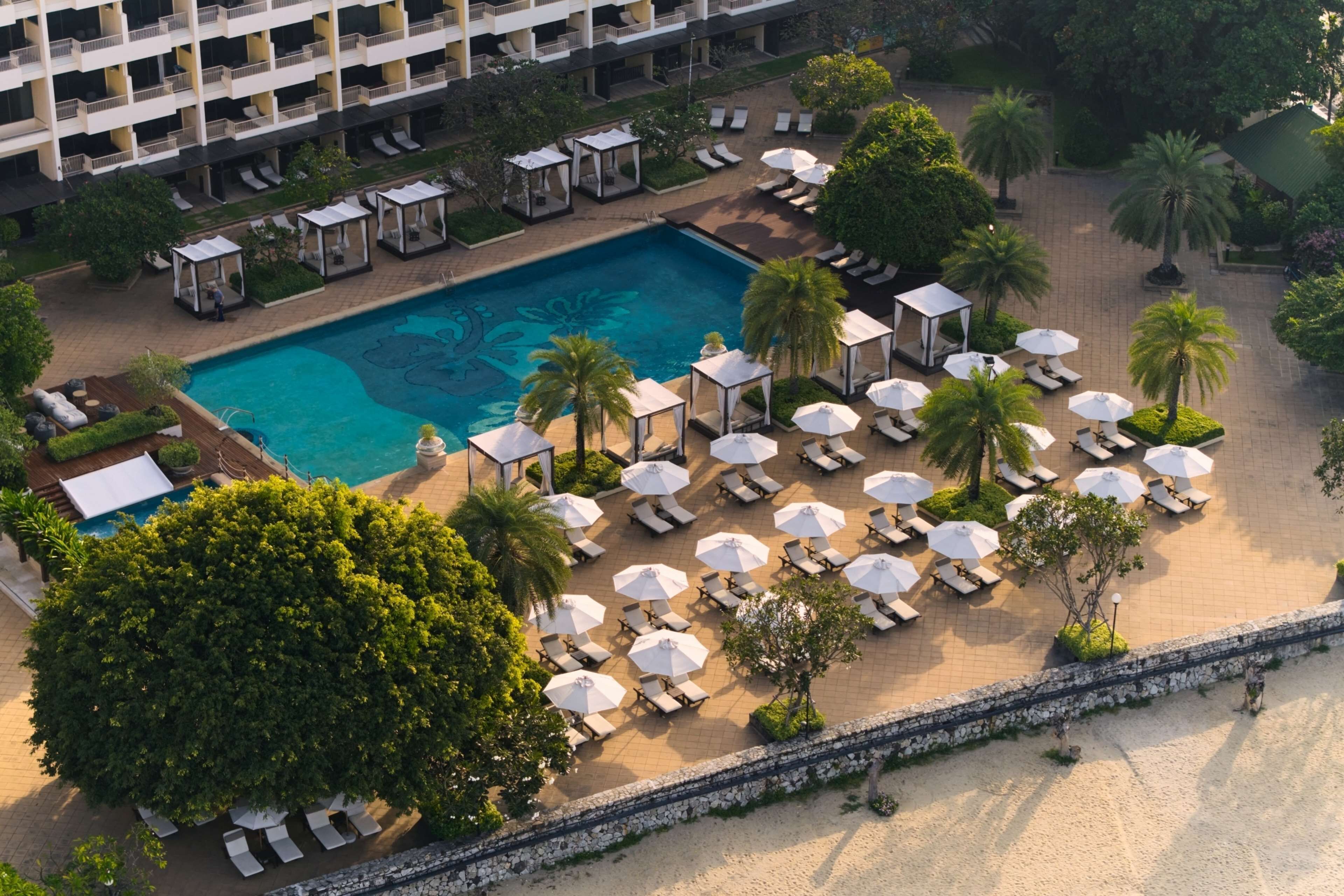 Vista aérea de un hotel con piscina, tumbonas y una zona de playa.