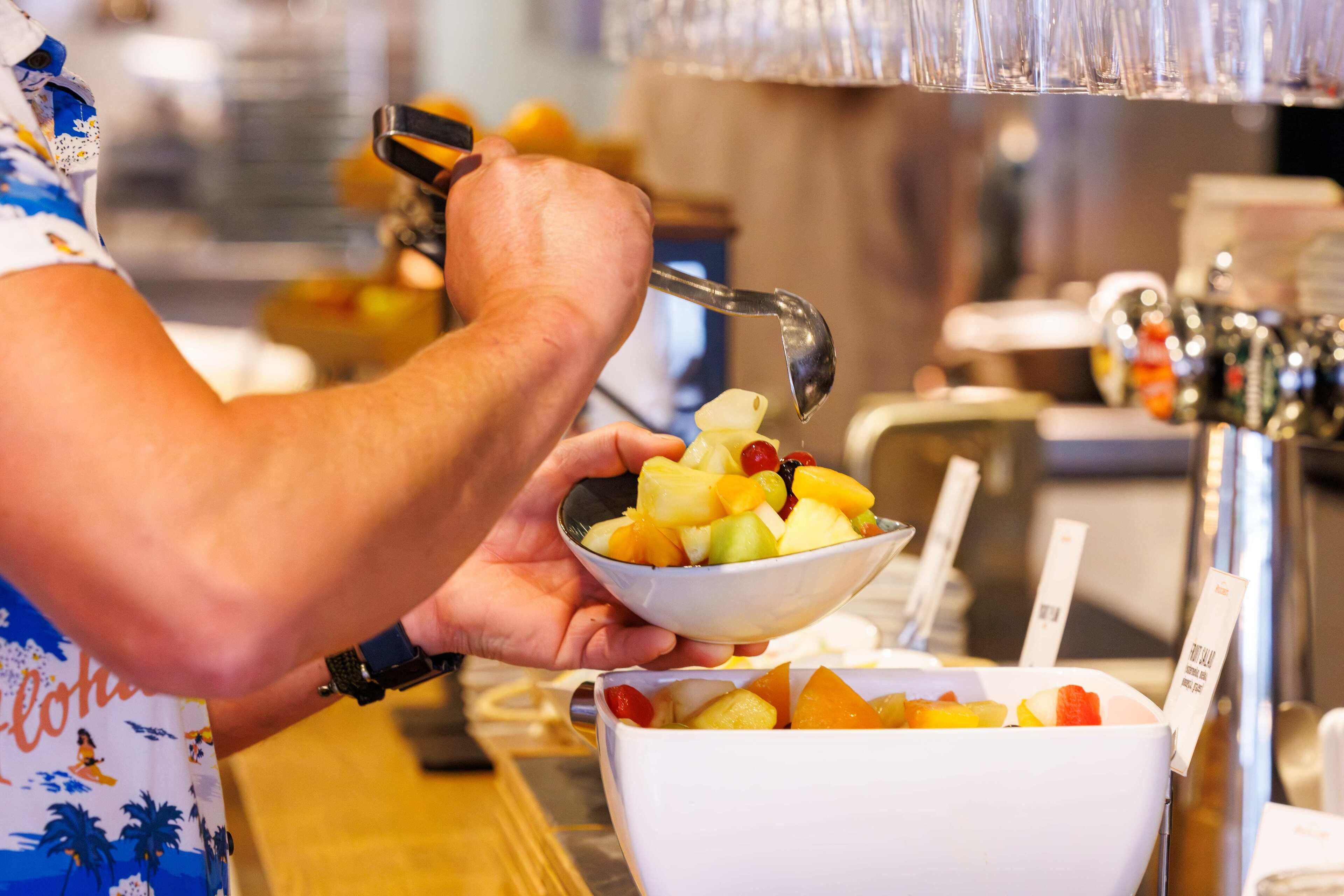 Iemand maakt een fruitschaal met verschillende soorten fruit.