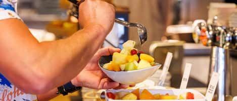 A person preparing a fruit bowl with a variety of fruits.