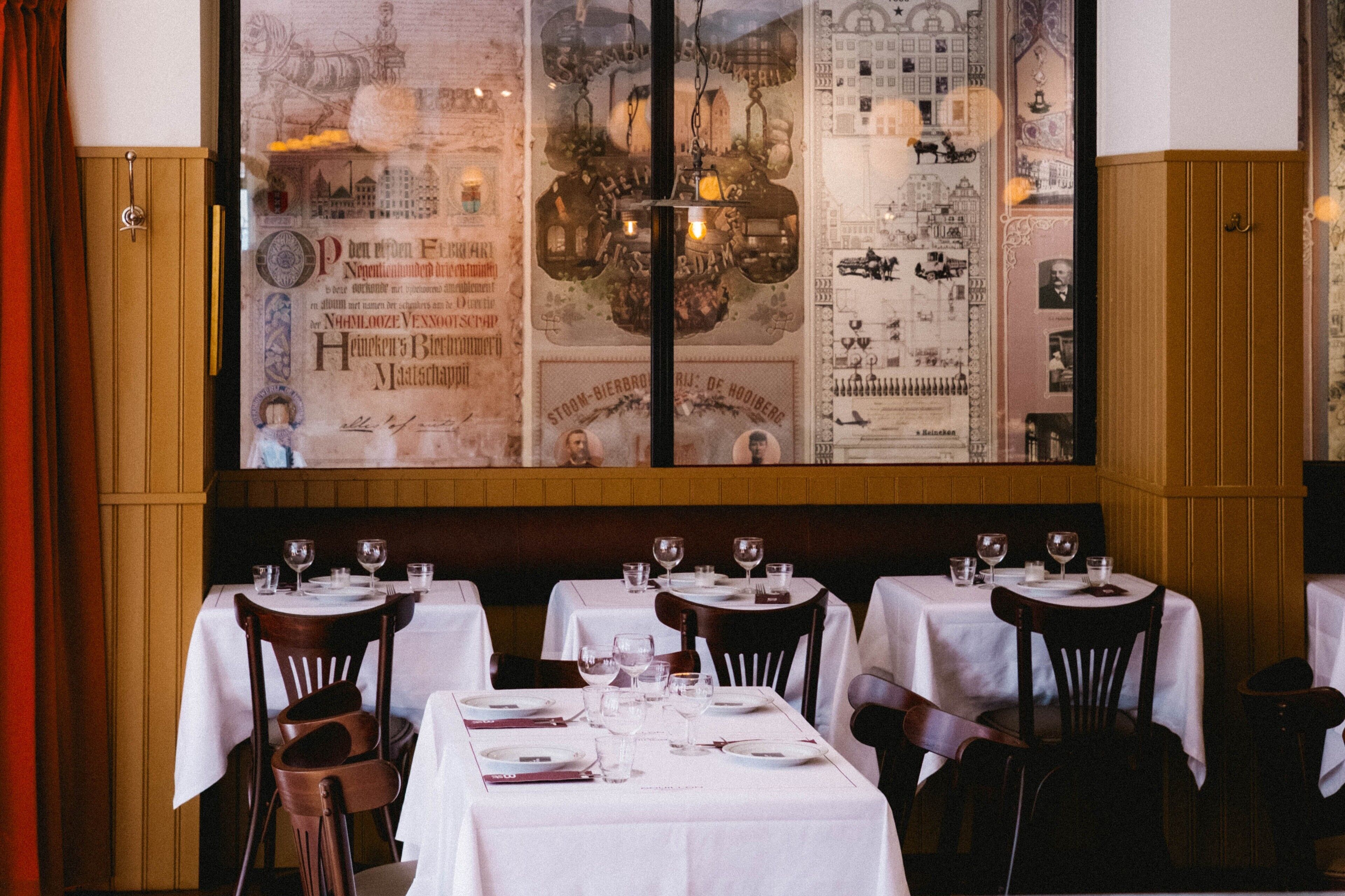 Un restaurante con mesas dispuestas para comer, un mural grande en la pared y paneles de madera.