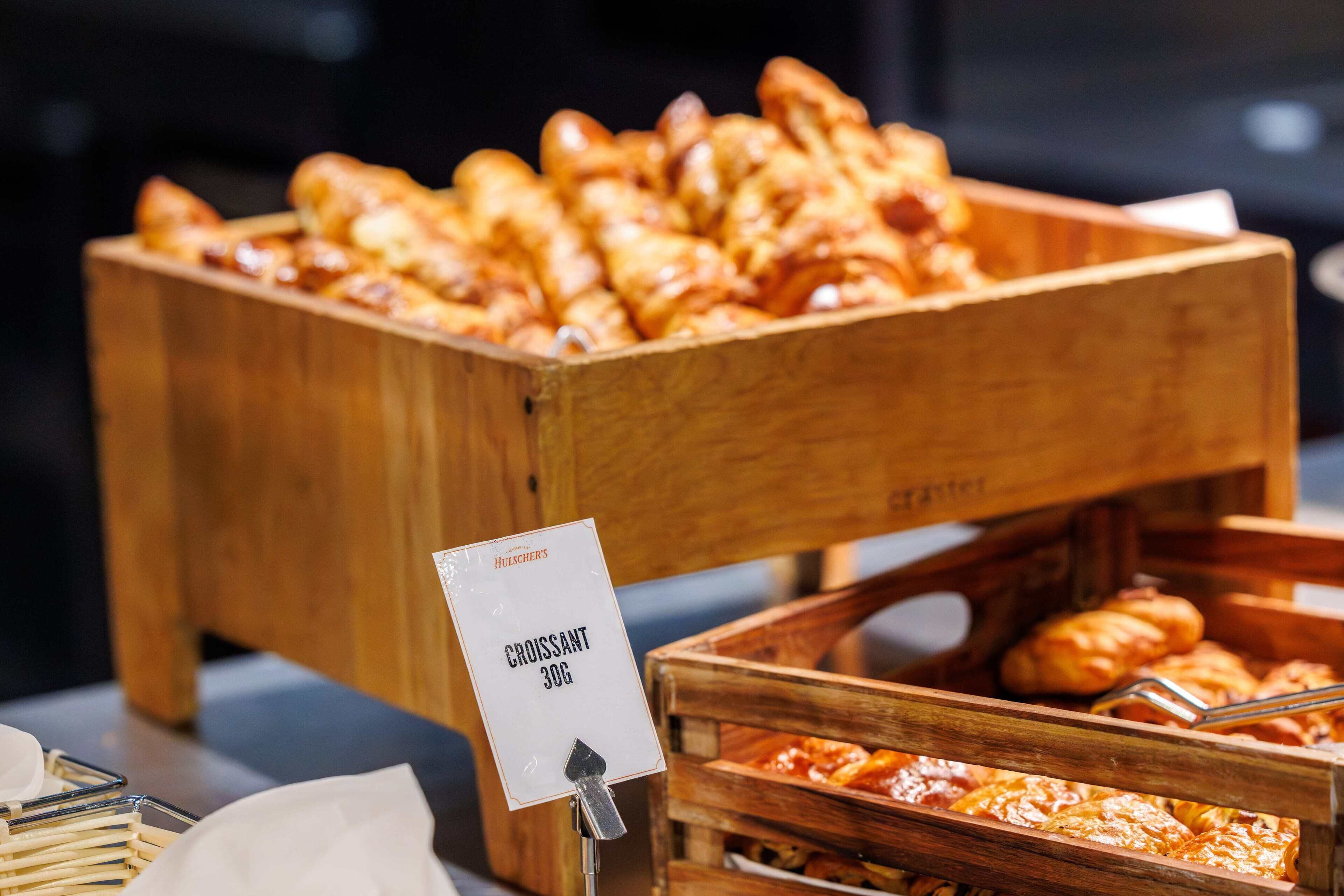 A wooden buffet display with a sign indicating 'CROISSANT 30G'.