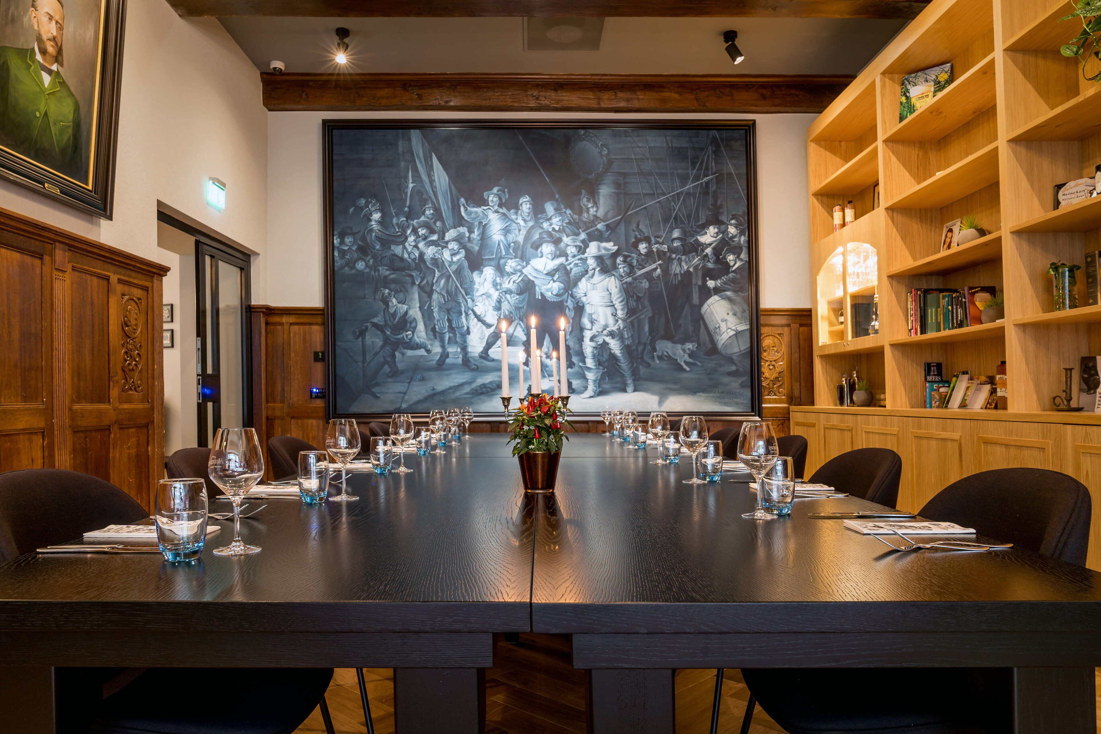 Een vergaderruimte met een lange tafel gedekt voor een vergadering, met houten lambrisering en een groot schilderij.