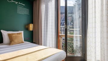 Een hotelkamer met een groot bed, een raam met uitzicht op gebouwen en een muur met tekst.