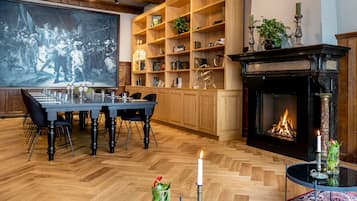 Una habitación amplia con una gran mesa de comedor de madera, una chimenea y una estantería llena de libros y objetos decorativos.