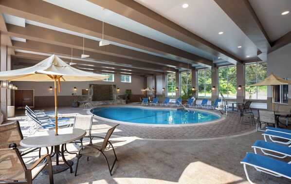 A pool area with lounge chairs, umbrellas, and a stone wall. - Holiday Inn Resort Lake George - Adirondack Area by IHG (Lake George)