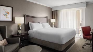 A hotel room with a large bed, two bedside tables with lamps, a chair, and a view of the outdoors through a window with curtains.
