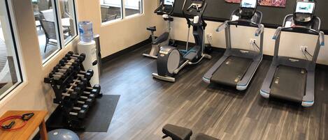A gym with treadmills, elliptical machines, dumbbells, and exercise balls.