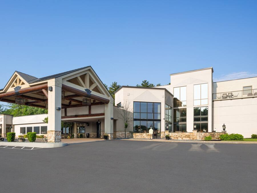 Un hotel con vestíbulo cubierto, amplias ventanas y fachada de piedra.