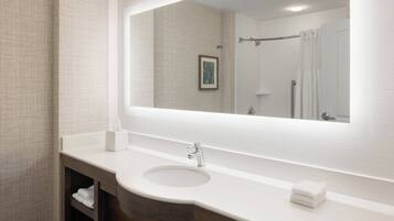 A bathroom with a large mirror, a sink, and a towel rack.