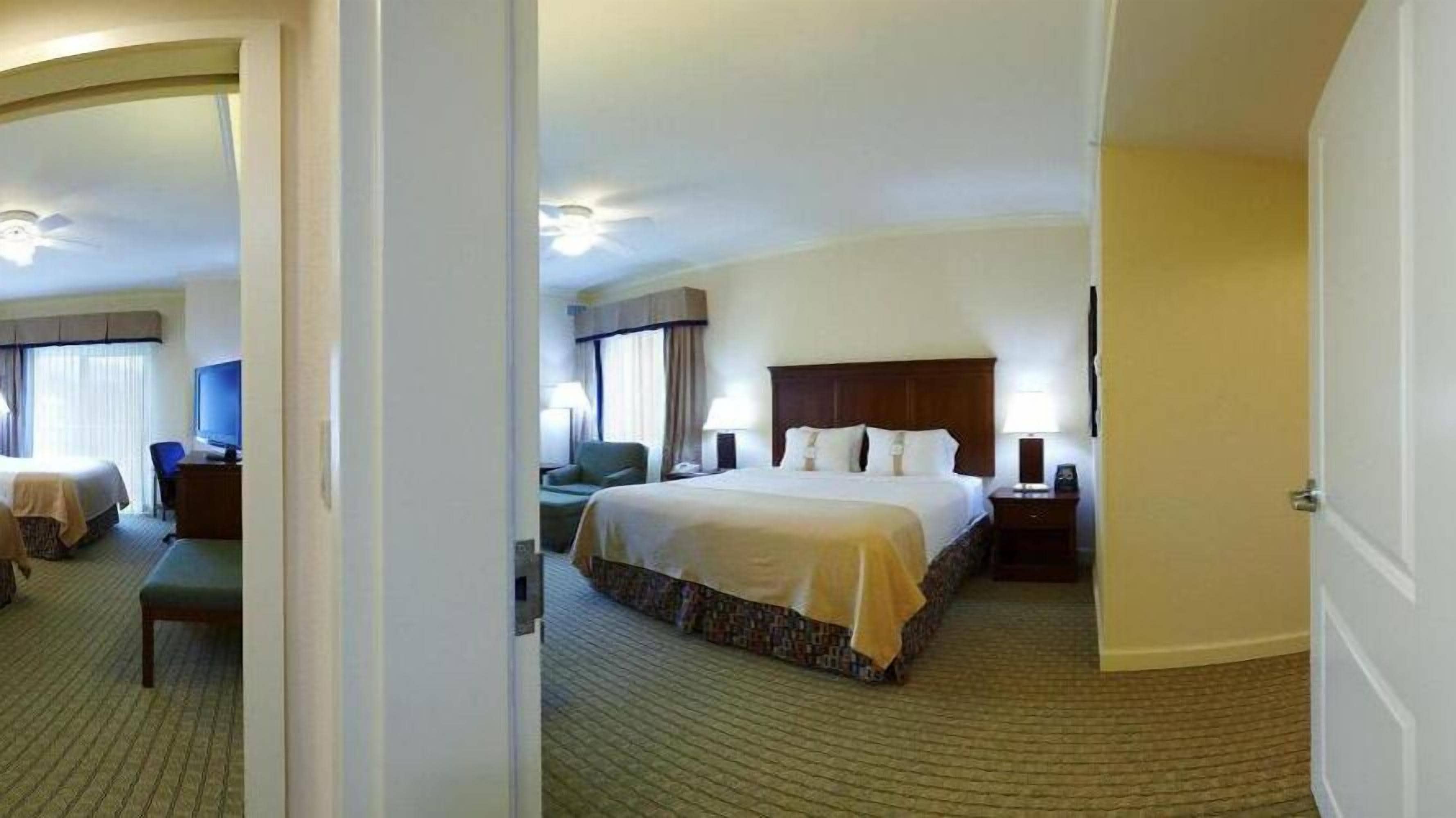 A hotel room with a large bed, a desk, a chair, and a television.