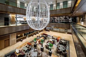 A spacious lobby with a large spherical light fixture, multiple seating areas, and a high ceiling.