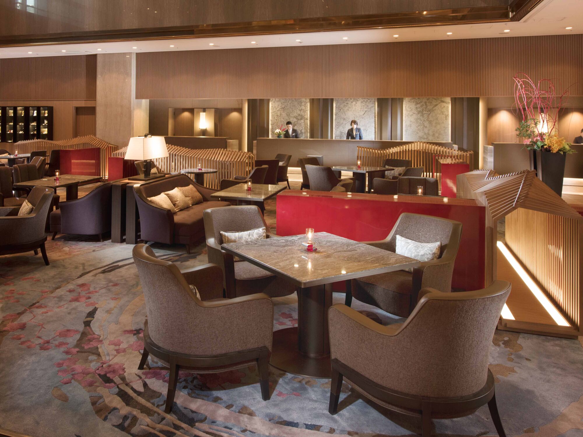 A modern hotel lobby with a reception desk, seating area, and a bar.