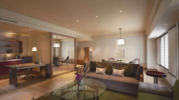 A modern living room with a glass coffee table, a sofa, and a dining area with a table and chairs.