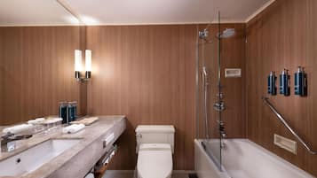 Un baño moderno con pared de paneles de madera, inodoro blanco, lavamanos de mármol y bañera.
