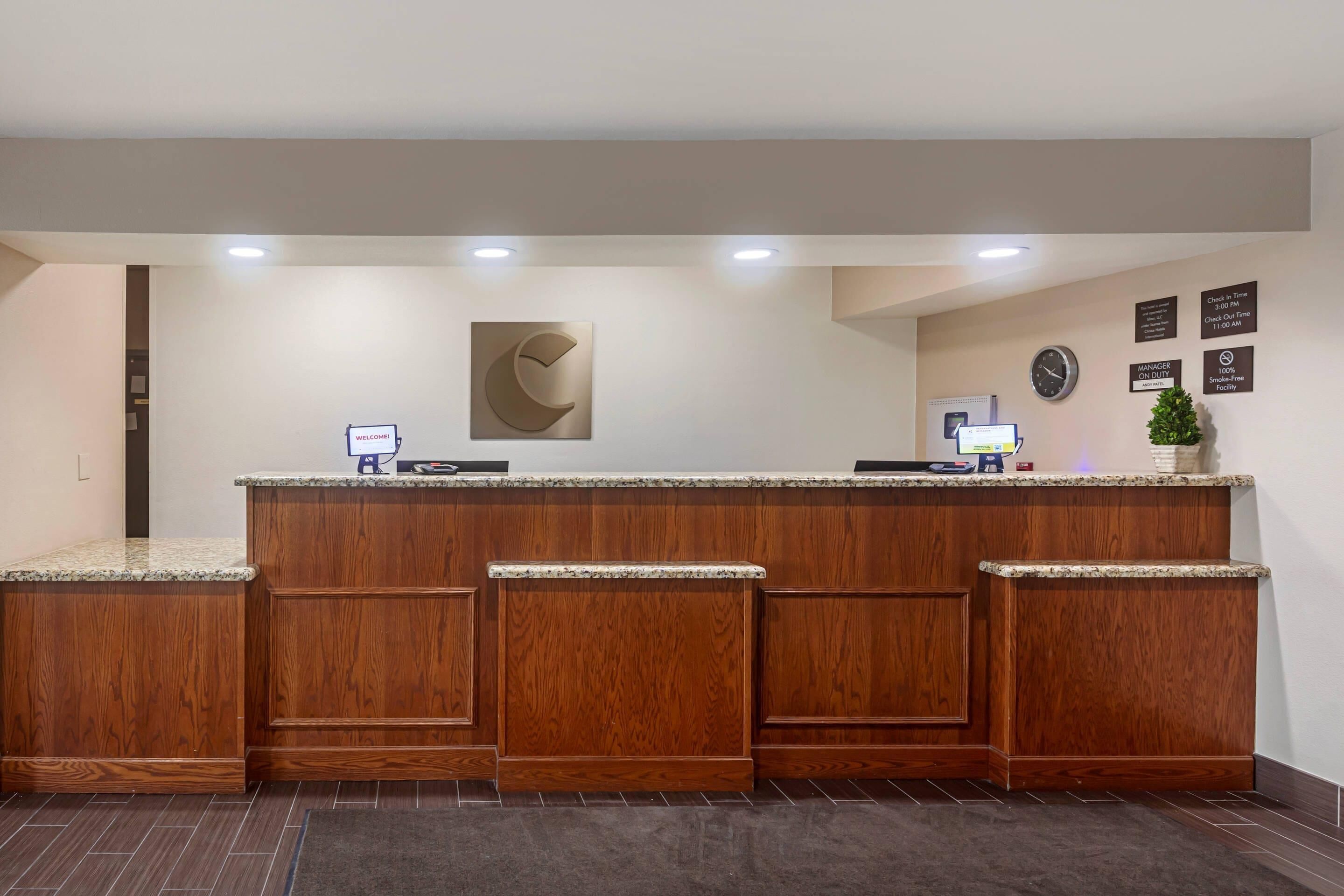 A reception desk with a wooden finish, a clock, and a welcome sign.