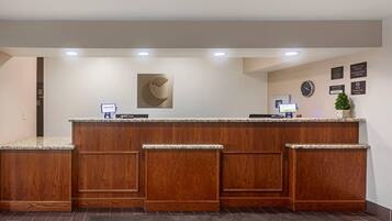 A reception desk with a wooden finish, a clock, and a welcome sign.