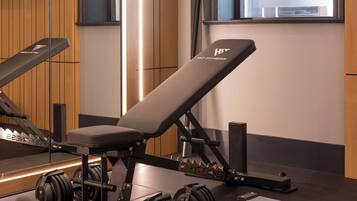 A modern gym with a bench press, kettlebells, and a rowing machine.