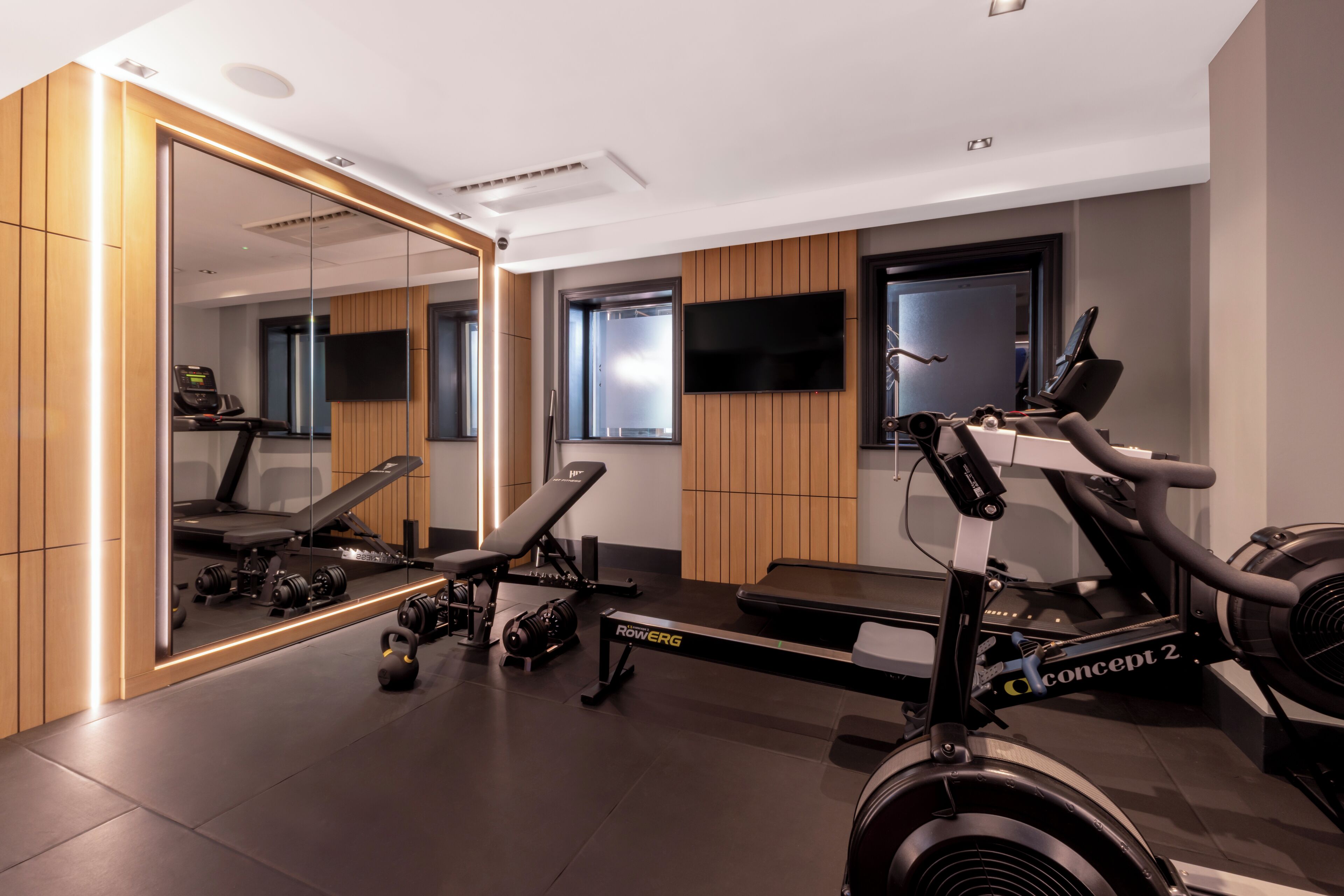 A modern gym with exercise equipment, a large mirror, and a television.