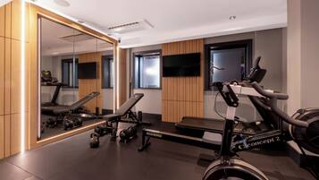 A modern gym with exercise equipment, a large mirror, and a television.