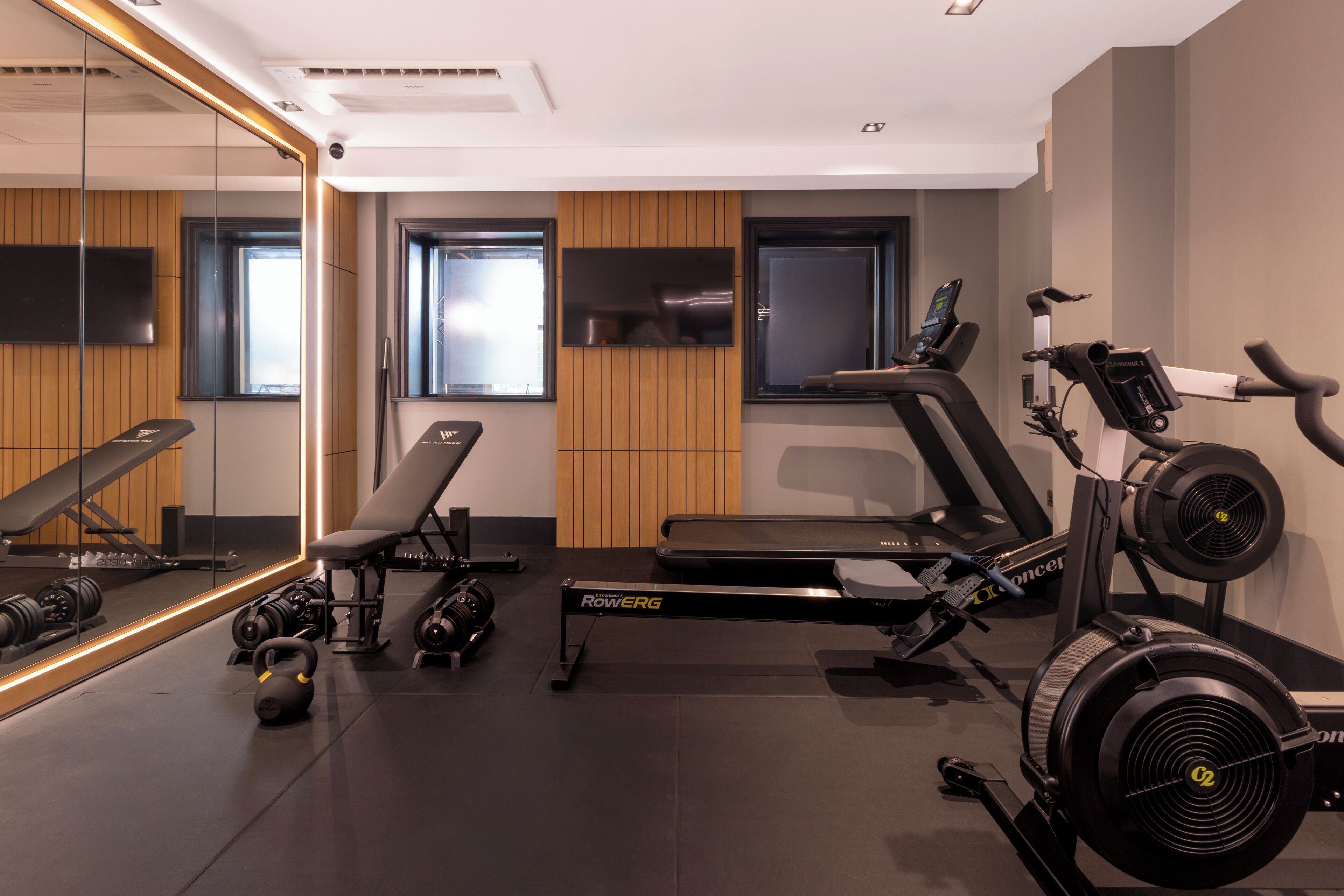 A modern gym with a treadmill, rowing machine, and weights.