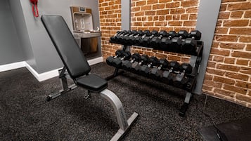 A gym with a bench, dumbbells, a water dispenser, and a red telephone.