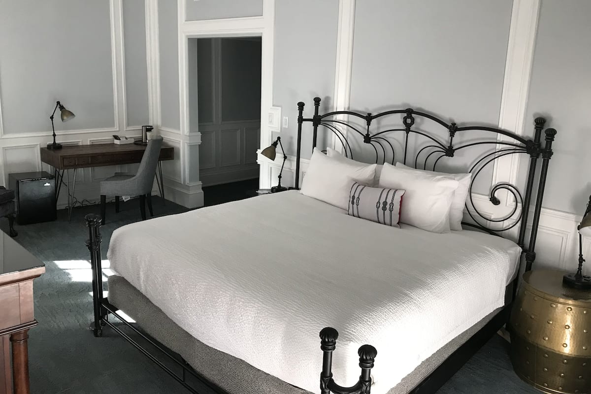 A neatly arranged bedroom with a large bed, a desk, and a chair.