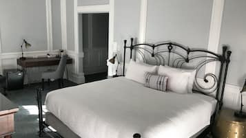 A neatly arranged bedroom with a large bed, a desk, and a chair.