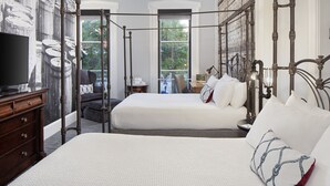 A four-poster bed with white bedding, a television on a wooden dresser, and a mural of barrels on the wall.