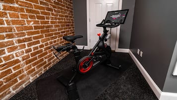 A stationary bike with a digital display in a room with a brick wall and a door in the background.