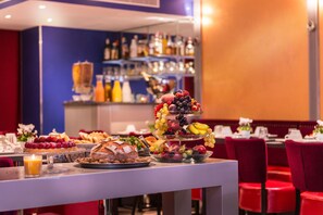 A buffet table with various food items and a bar area in the background. - Hotel Monceau Wagram (Paris)