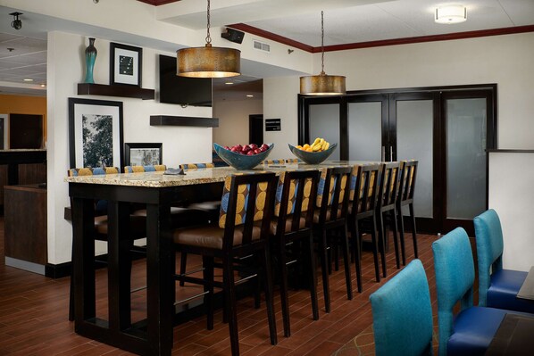 Una cocina con una isla central, taburetes de bar y una zona de comedor con sillas.