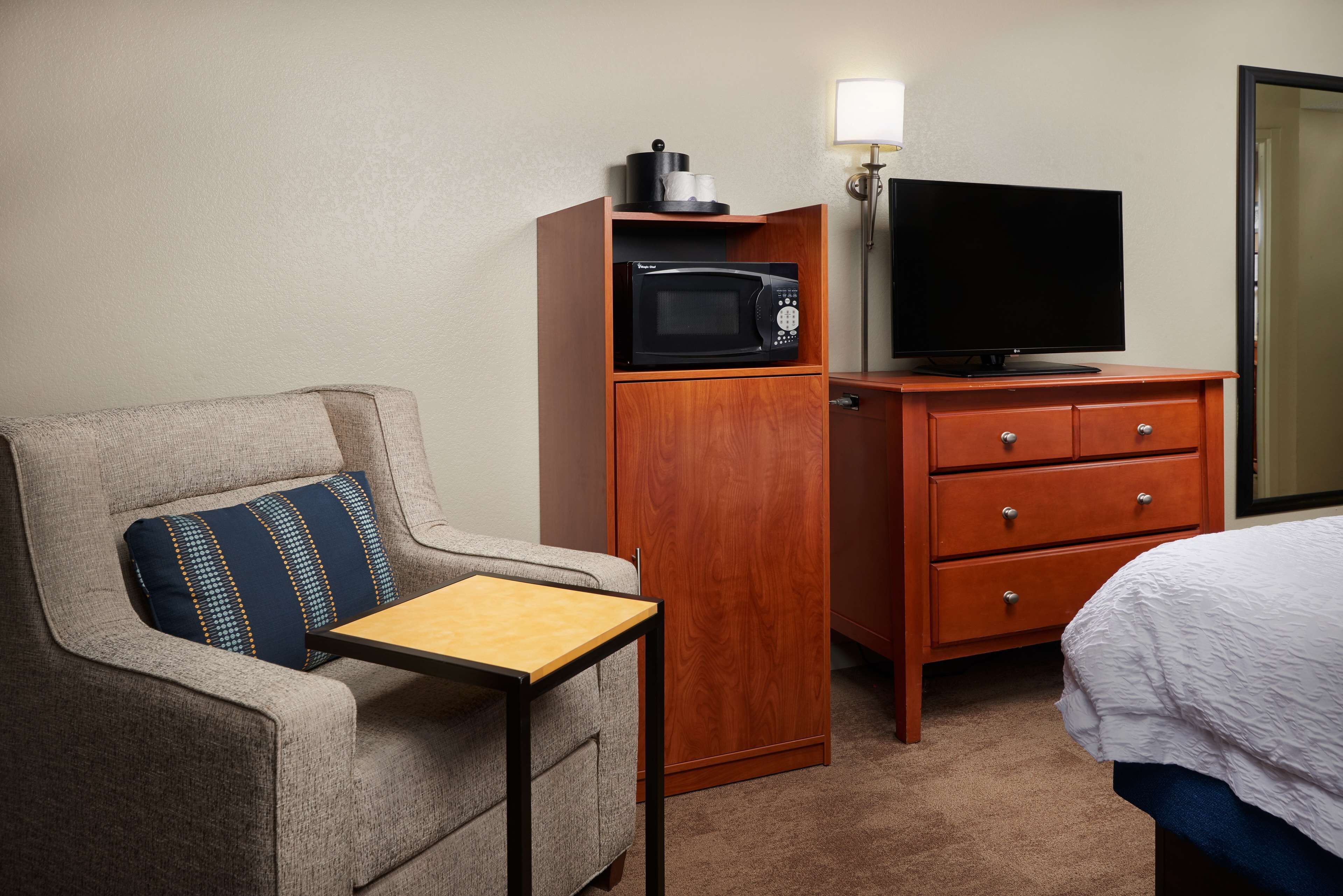 Ein Hotelzimmer mit Sofa, einem Holfachschrank mit Mikrowelle, Fernseher und einem kleinen Tisch.