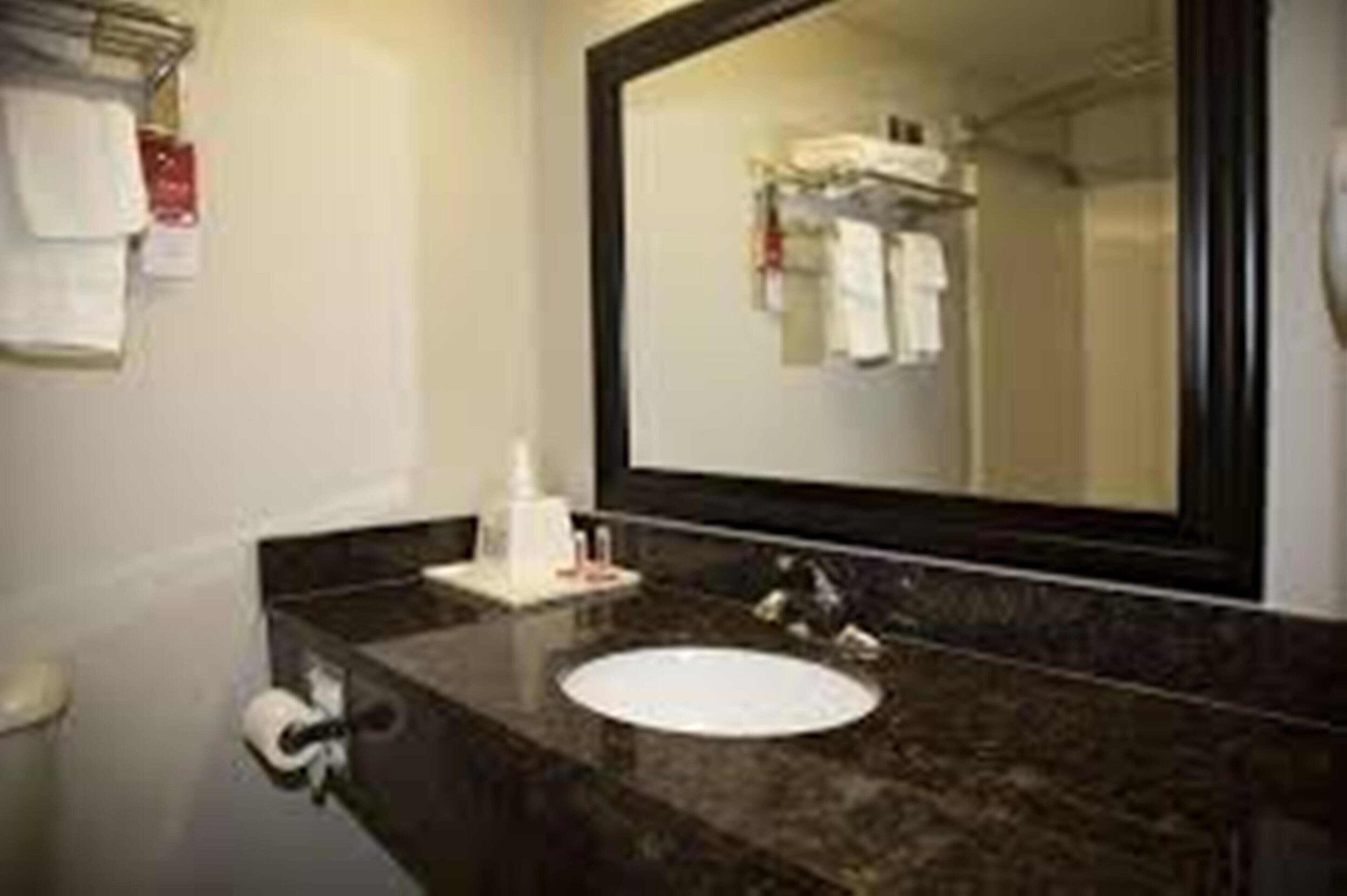 A bathroom with a sink, mirror, and towel rack.