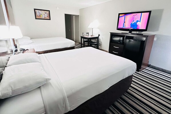 A hotel room with two beds, a television, a desk with a chair, and a lamp. - Econo Lodge Ardmore (Ardmore)