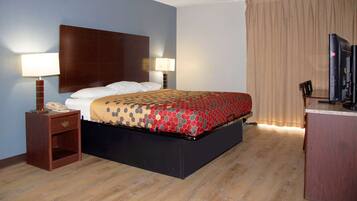 A hotel room with a bed, two bedside lamps, a desk with a computer, and a TV.