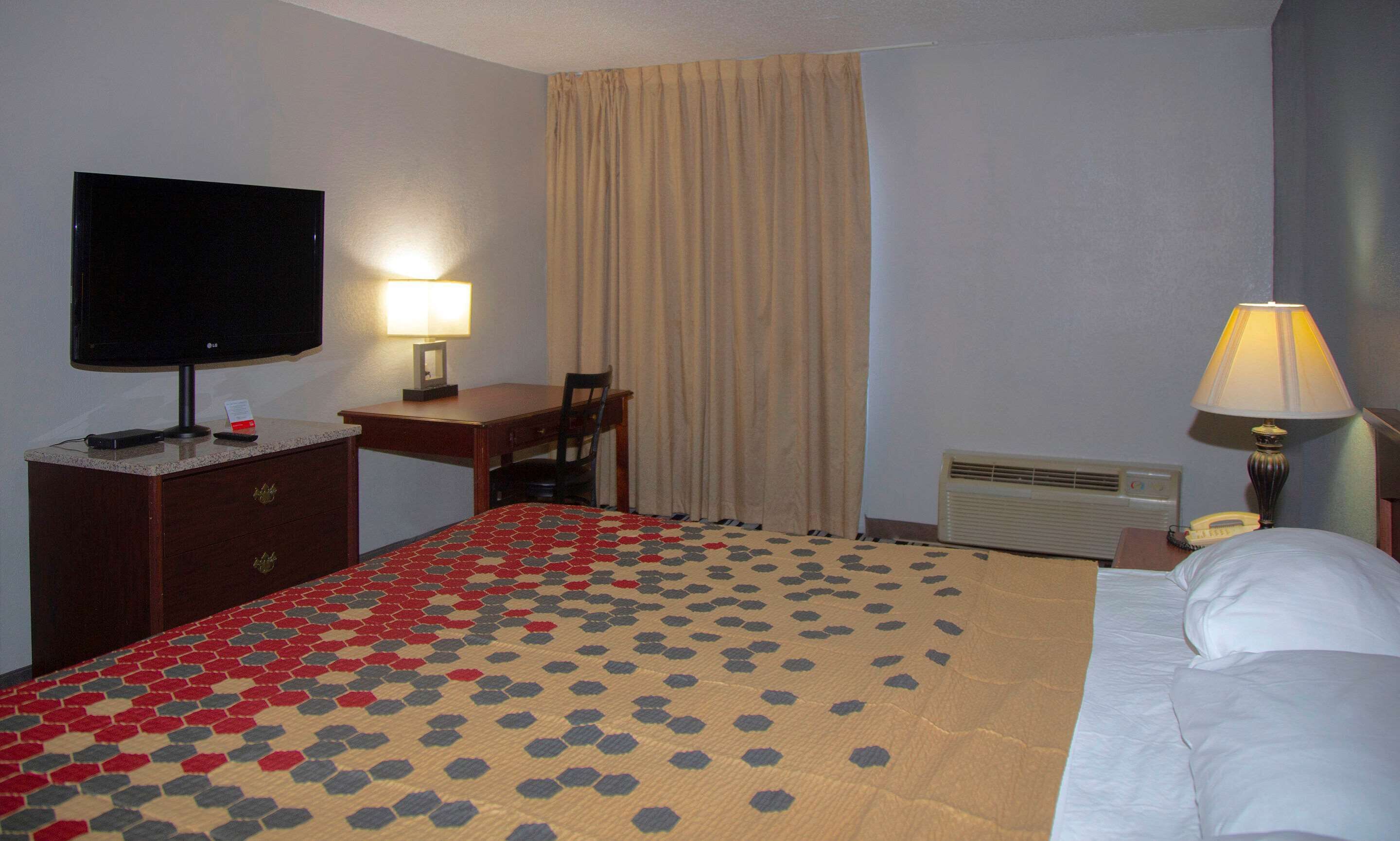 Une chambre d’hôtel équipée d’un lit, d’un bureau, d’une chaise, d’une télévision et d’une lampe.
