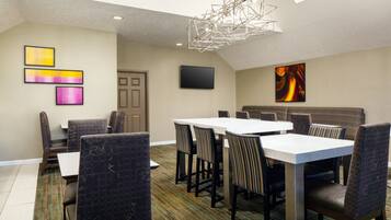 A conference room with a high ceiling, a modern chandelier, and a large painting on the wall.