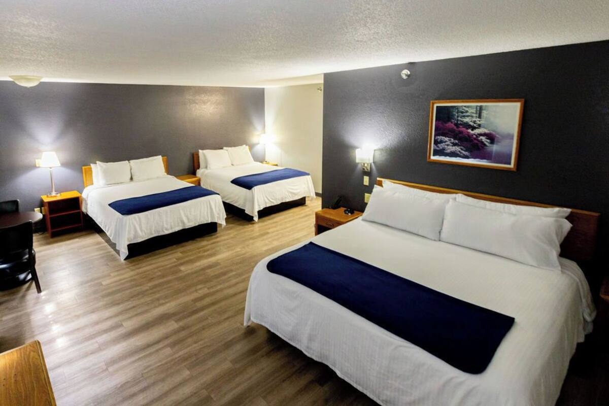 A hotel room with two beds, a desk, and a chair.