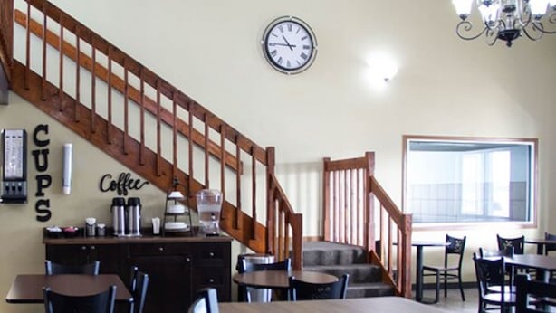 A dining area with a wooden staircase, a clock, and a coffee station. - New Victorian Inn Norfolk (Norfolk)
