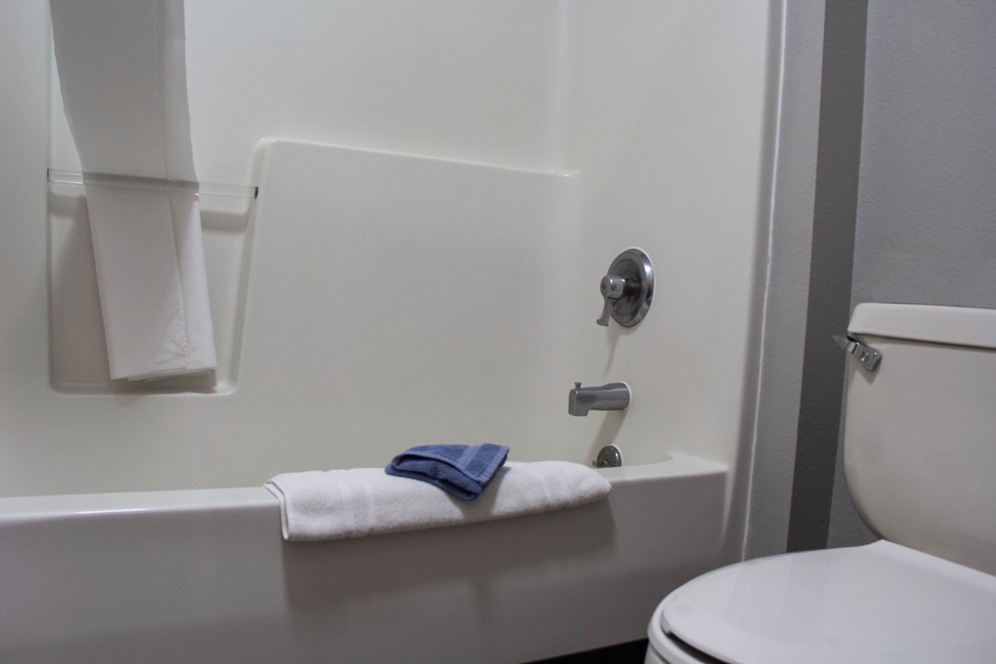 A bathroom with a bathtub, a toilet, and a towel rack.