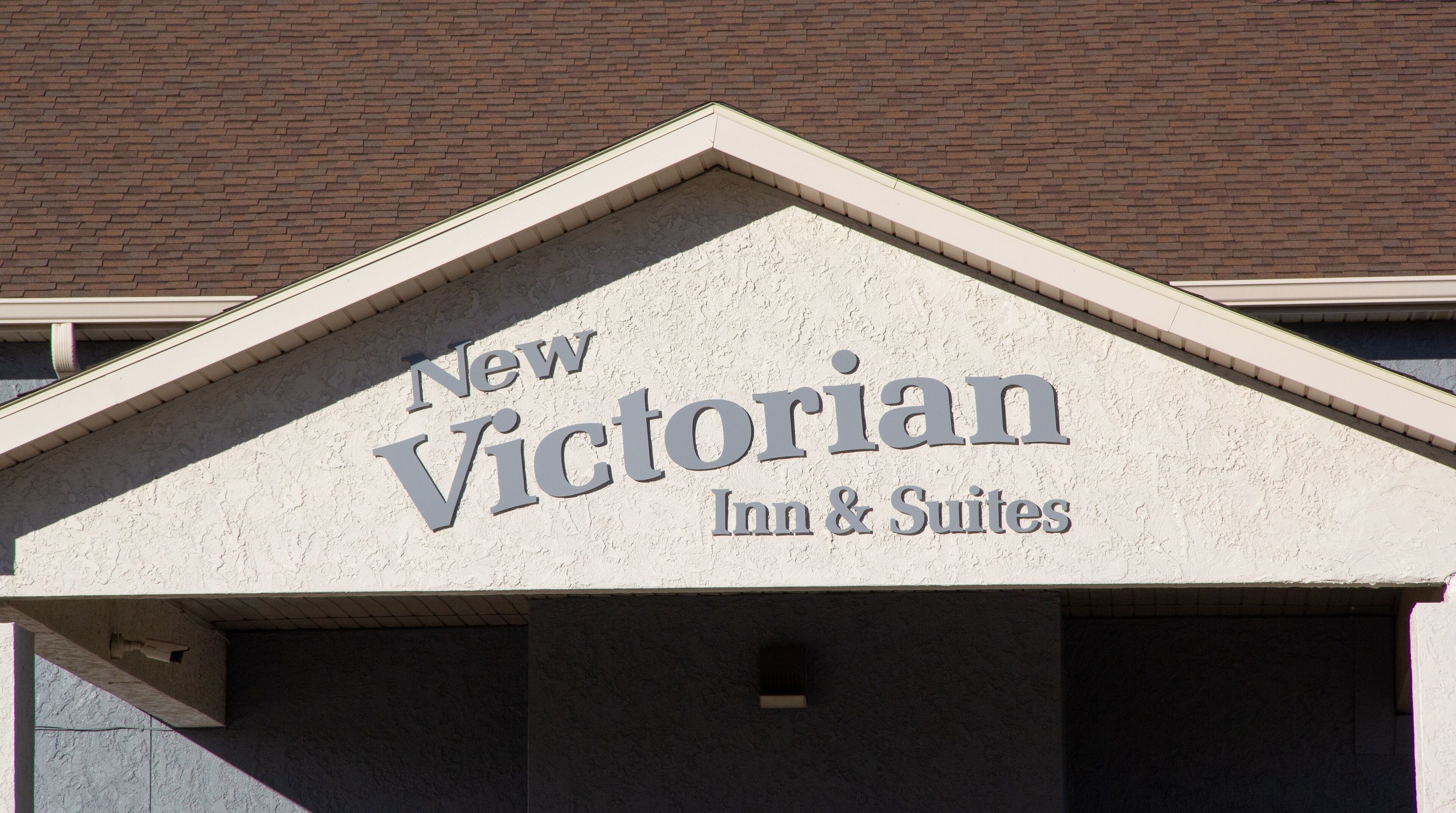 A building with a sign that reads "New Victorian Inn & Suites".