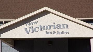 A building with a sign that reads "New Victorian Inn & Suites".