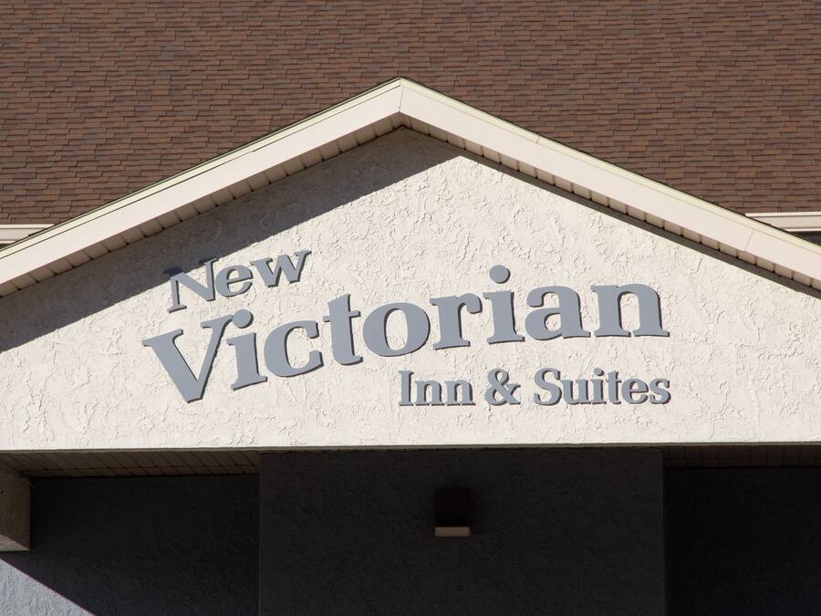 A building with a sign that reads "New Victorian Inn & Suites".